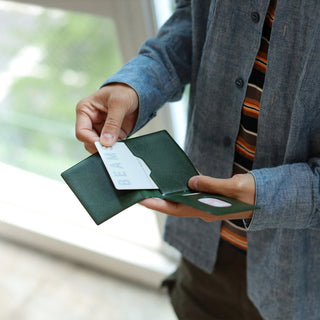 Green leather card case opened, showing inner card sleeve and slots