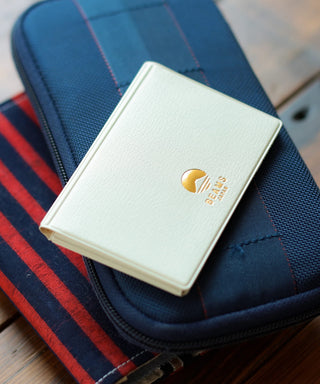 White leather card case with gold logo on front