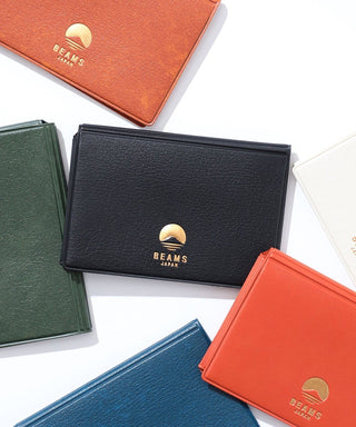 Assorted leather card cases in green, black, blue, and orange with gold logos