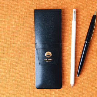 Navy leather-look pen case with BEAMS Japan logo patch beside a pen.