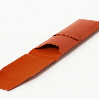 Terracotta leather-look pen case with rolled flap opening and stitched edge.