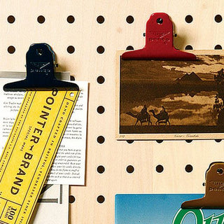 Navy steel binder clip holding documents on a polka-dot notebook