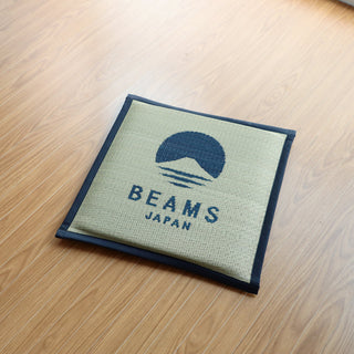 Navy-bordered BEAMS JAPAN logo cushion on light fabric with stitched edges