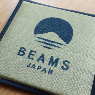 Close-up BEAMS JAPAN logo cushion in light fabric with navy print and border