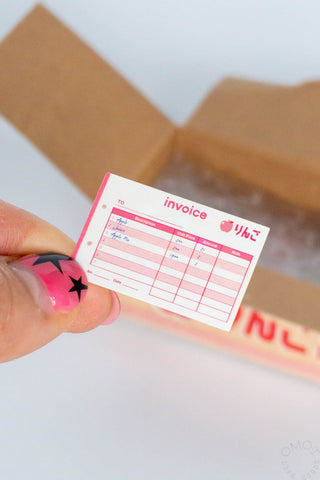 Pink invoice sticker seal label with red grid, held by a hand