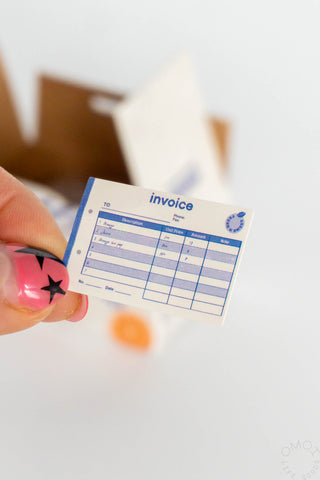 Invoice sticker seal label with blue grid table, held by a finger