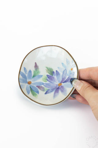 Round mini plate with blue and purple flowers, gold rim, held by a hand