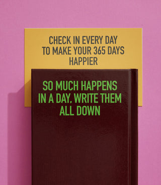 Closed diary notebook with yellow top cover text, dark panel, and green string tie.