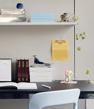 Stack of 365 diary notebooks on a desk with an open notebook and desk items