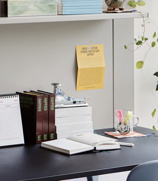 365 diary notebooks on desk with a small yellow notepad and open planner pages