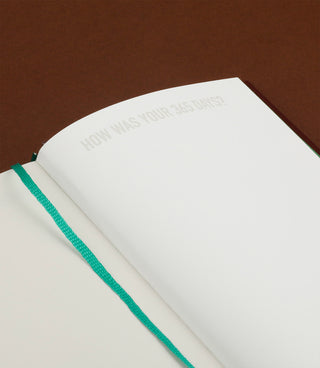 365 diary notebook closed in white cover with green elastic strap