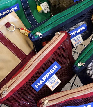 Close-up of mesh layer pouches with zippers, HAPPIER logo patches, and key clips