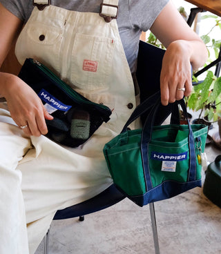 Translucent mesh pouch with top zipper, green with blue trim, held in hand