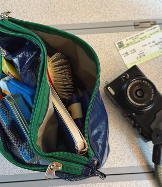 Open green-mesh layer pouch with contents, visible zipper track and metal key ring
