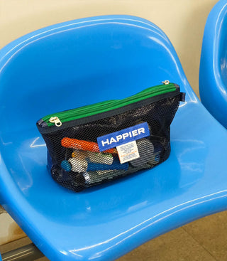 Dark mesh pouch with green zipper and HAPPIER logo patch, holding small items