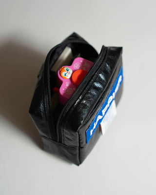 Black tofu pouch open with zipper and small items inside
