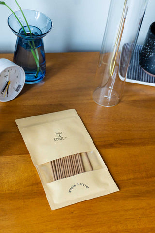 High & Lonely incense bag laid on a table, with wooden incense sticks visible