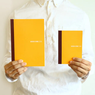 A5 graph notebook pair held up, orange covers with dark spine stripe