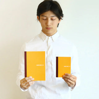 A5 graph notebook set held up, orange covers with dark side stripe
