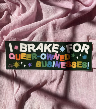Green bumper sticker reading "I BRAKE FOR QUEER-OWNED BUSINESSES" with starburst icons