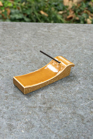 Terracotta incense burner tray with holder and inserted incense stick, glossy orange glaze