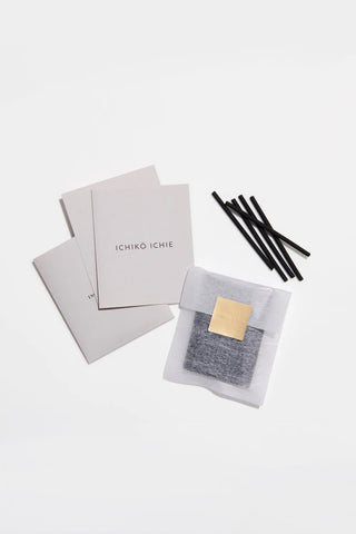 Osmanthus incense set with black sticks, white packets, and gray sachet