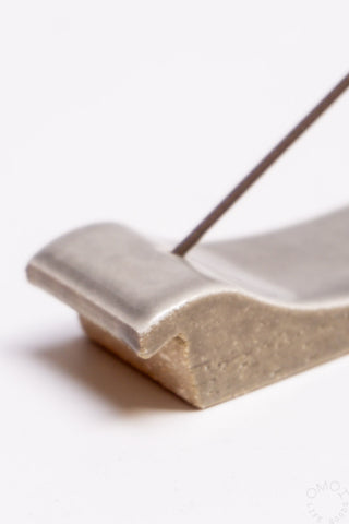 Grey clay incense burner with curved holder and slender incense stick