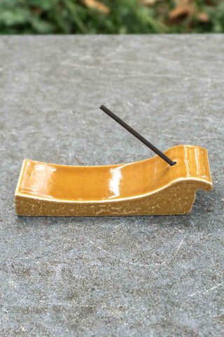 Terracotta incense burner with raised sides, incense stick inserted, glossy orange glaze