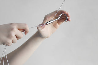 Hanging plant pot with wire hanger being adjusted by hands, close-up view