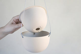 Hanging plant pot planter in light finish with wire straps and small drainage holes