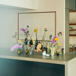 Brown glass vase on kitchen shelf with colorful flower stems