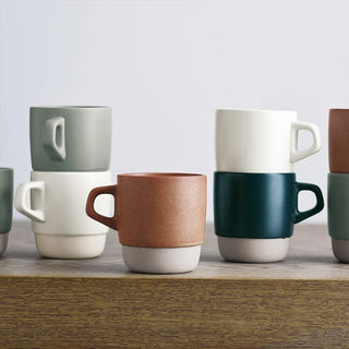 Ceramic stacking coffee mugs in mixed colors with white bases and curved side handles