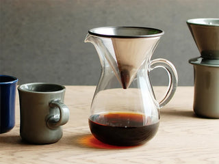 Glass coffee carafe with stainless cone top and handle, filled with dark coffee