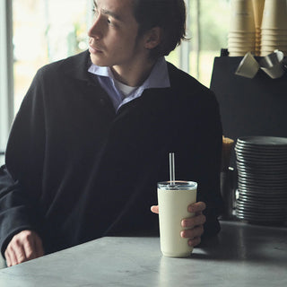White 480 ml insulated tumbler with straw on table, clear lid with straw opening