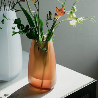 KINTO TRE amber glass vase with flared top, holding green stems and orange flowers.