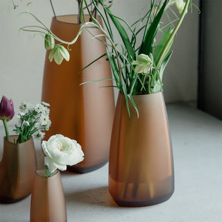 KINTO TRE glass vases in amber tones with flared openings, arranged with flower stems.