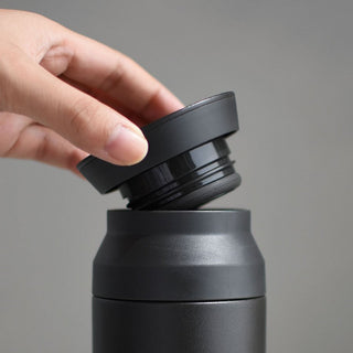Black 500ml travel tumbler lid close-up being pressed, showing inner seal