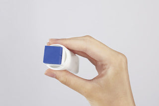 Glue stick held to paper corner, showing blue adhesive face