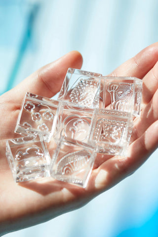 Hand holding clear engraved stamp blocks with geometric and floral patterns