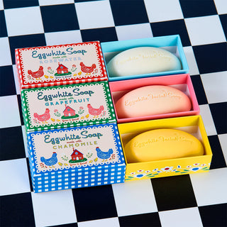 Open box of eggwhite facial soap bars in yellow, pink, and light green with labels