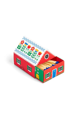 Red matchbox-style cottage with floral roof, arched doorway, and four green window panels