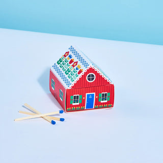 Red matchbox cottage house with blue windows, open door, and matchsticks