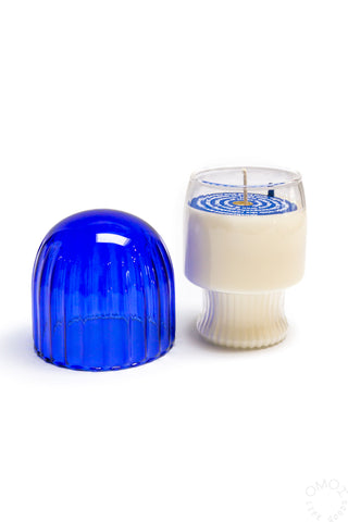 Blue glass mushroom candle cloche beside white jar candle with blue swirl