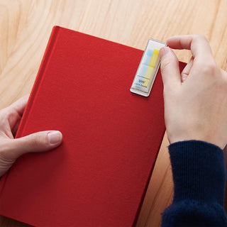 Hand pressing pastel sticky notes onto a red notebook cover