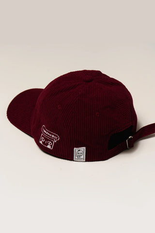 Burgundy corduroy baseball cap with side labels and adjustable strap