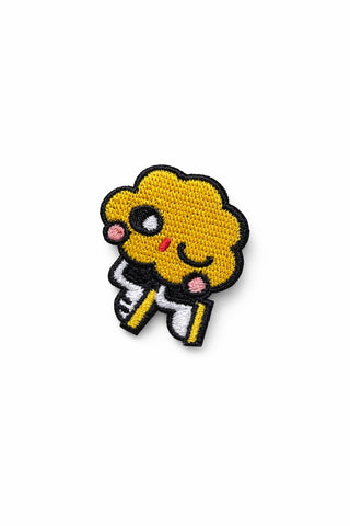 Small embroidered pin featuring a yellow skater character with black outline and smile