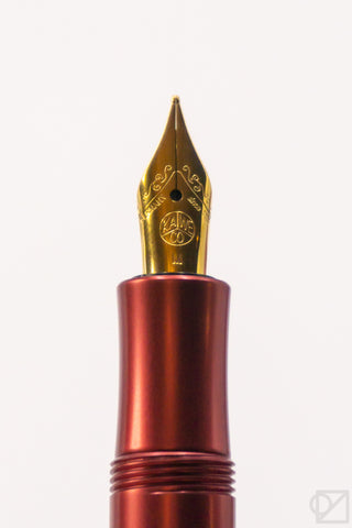 Close-up of gold fountain pen nib on ruby barrel