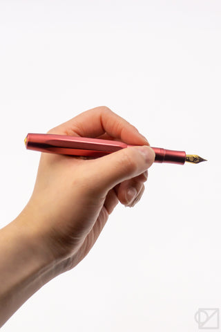 Hand holding ruby red fountain pen with gold nib