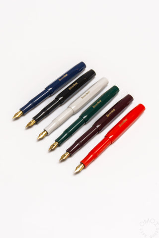 Fountain pen assortment showing six colors: navy, black, white, green, maroon, red