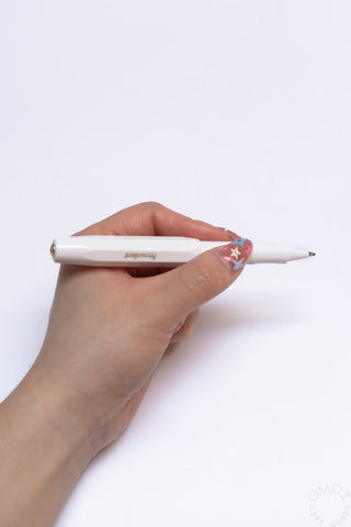 Hand holding a white Kaweco Sport rollerball pen with gold clip and nib